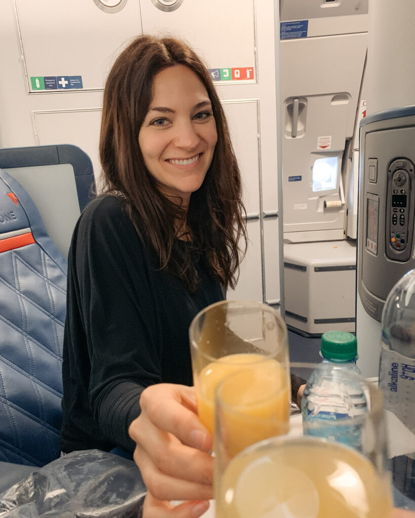 Enjoying mimosas in Delta One, experiencing premium in-flight service and luxury seating on a first-class flight for an elevated travel experience.