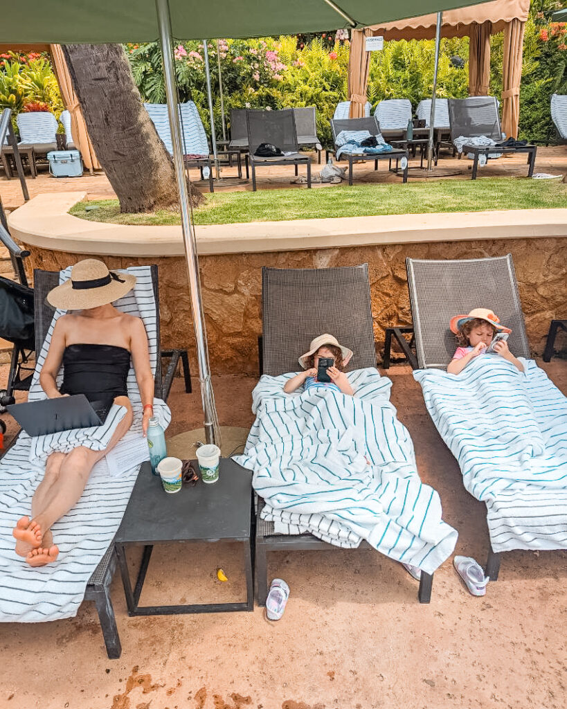  Mom and daughters relaxing poolside at the luxurious Grand Hyatt Resort & Spa in Kauai, a 5-star resort booked for free using Hyatt points and flexible reward points. Photo by Kevin Schadt.