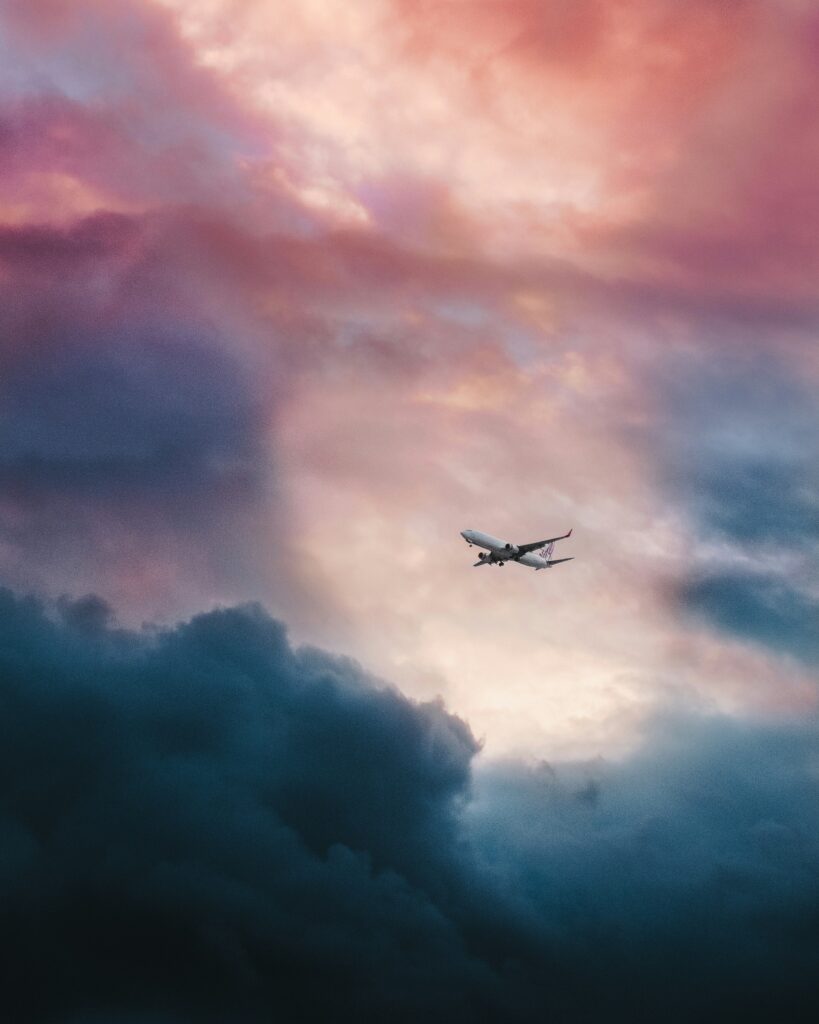 Airplane soars through a sunset sky, symbolizing the enhanced value of transferring credit card points to travel partners for maximum rewards. Photo by Leio Mclaren