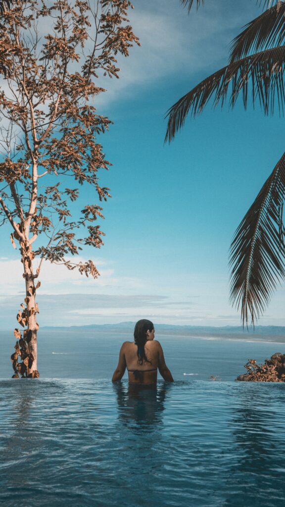 Woman relaxing in a stunning resort pool, showcasing the luxury hotels you can book with points and miles. Maximize value by transferring points to travel partners. Photo by Maximilien T Sharner.